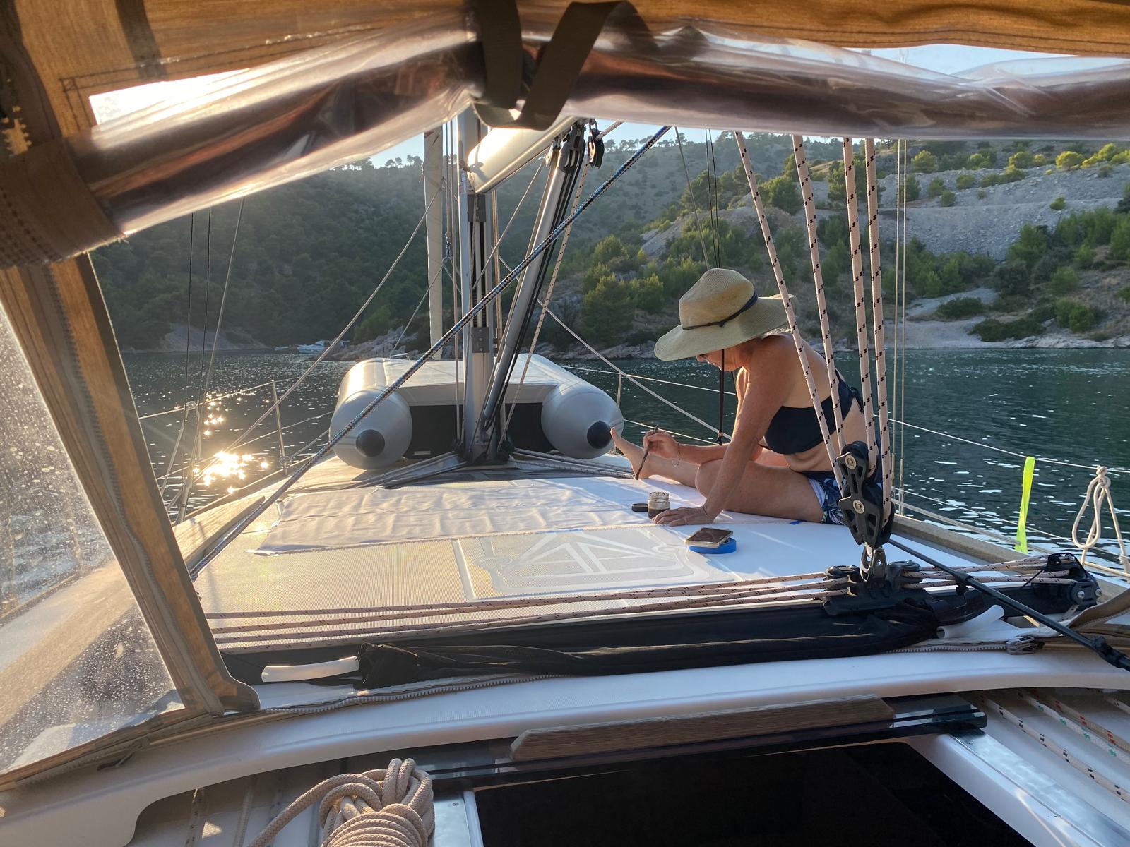 artist painting on the front of a sailboat